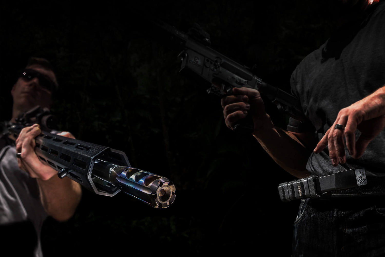 Two armed individuals in a dark setting, showcasing advanced weaponry in action