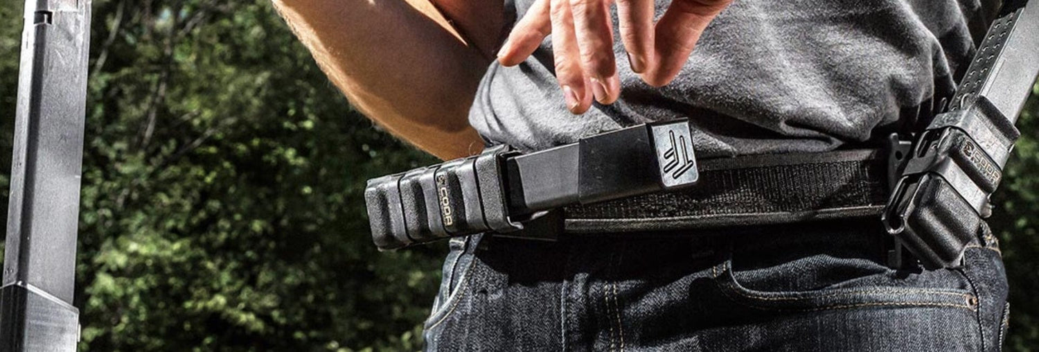 Close-up of a person adjusting a stylish black belt outdoors, reflecting codaevolution's innovation