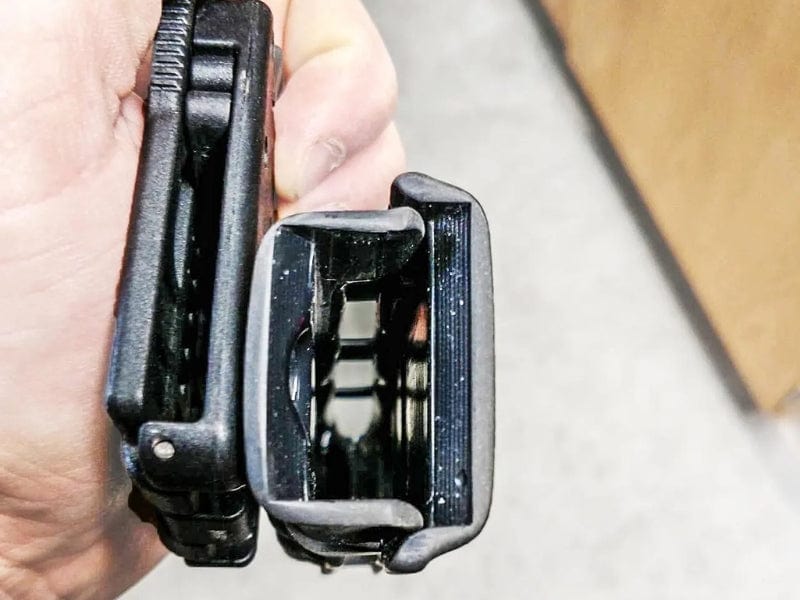 Close-up view of hand holding two different black tools with distinct designs and features