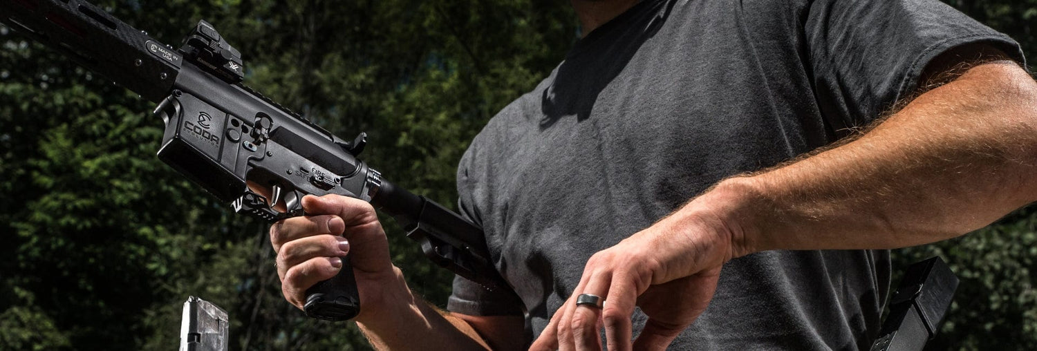 Close-up of a person holding a tactical rifle outdoors, showcasing focus on firearm handling