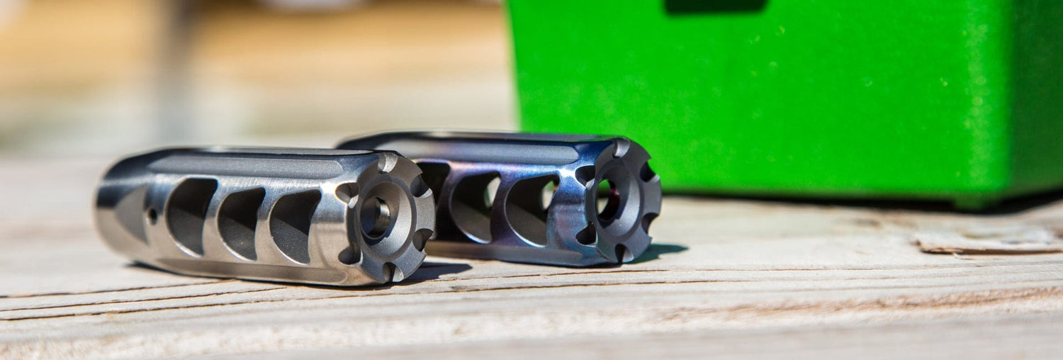 Close-up of high-quality stainless steel muzzle devices on a wooden surface