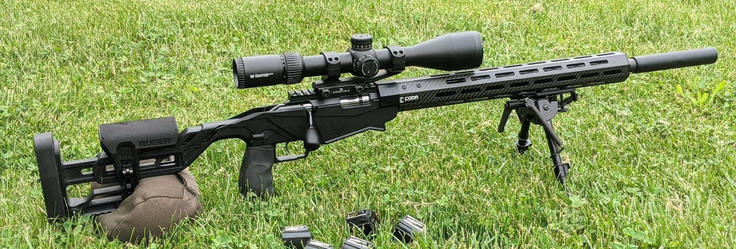 Precision rifle with scope and bipod on green grass, showcasing its sleek design and features