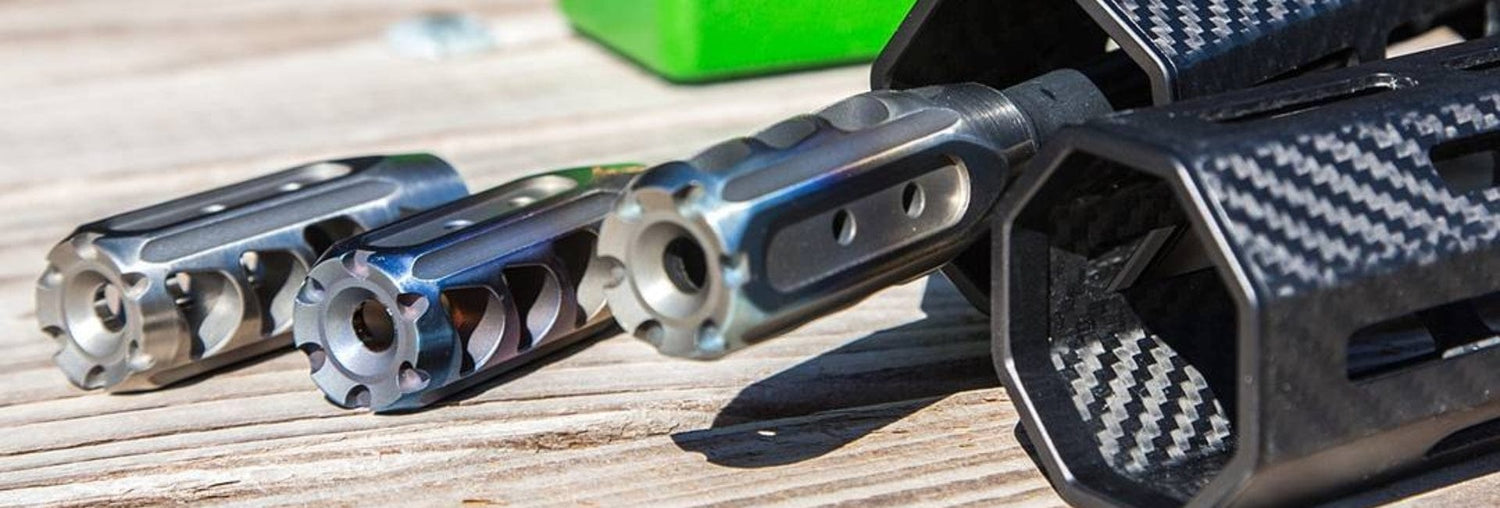 Close-up of precision-engineered gun muzzle devices on a wooden surface