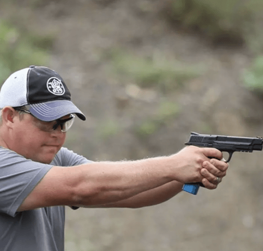 Person practicing firearm handling at a shooting range with a handgun in focus